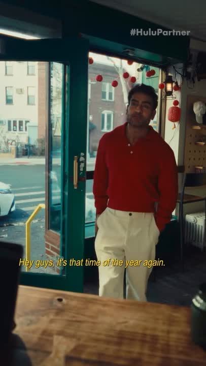 A man in a red shirt standing at a cafe door