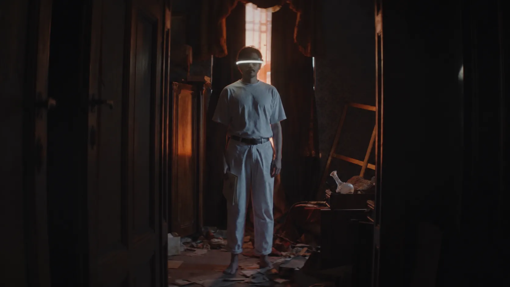 A man in a glowing visor standing in a dark room